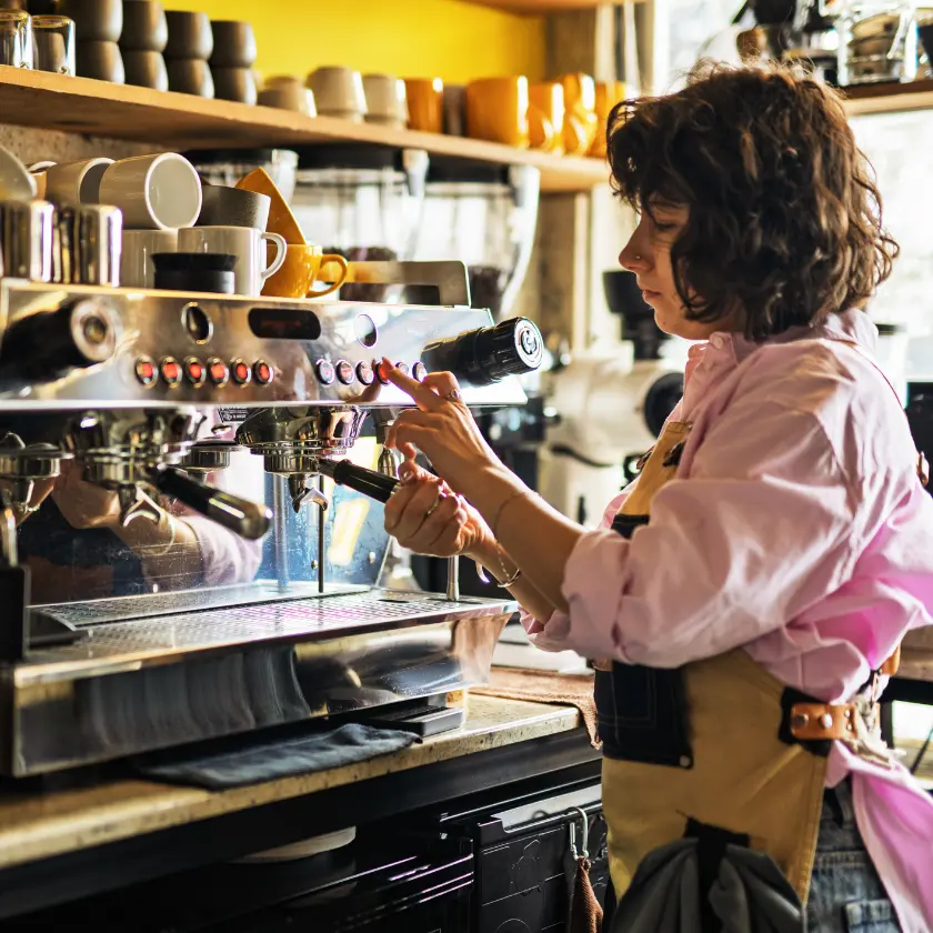 Barista working an espresso machine behind the counter of a cafe