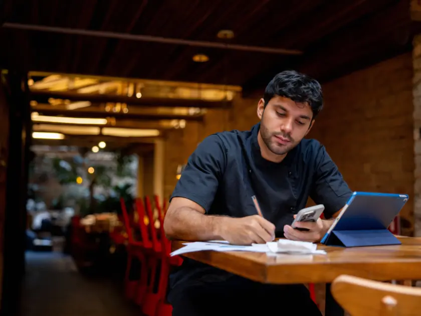 Chef doing paperwork with a tablet at a table in a restaurant