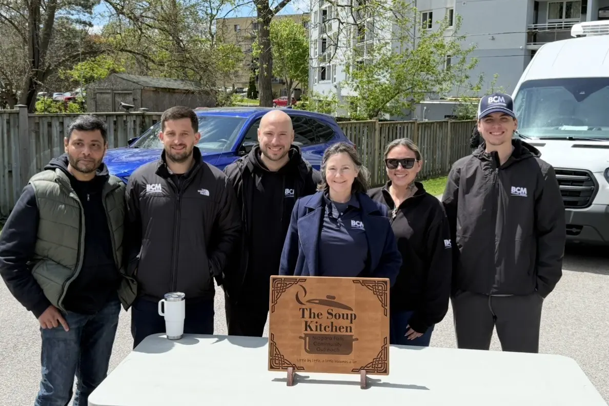 Six BCM Insurance staff standing behind a Soup Kitchen sign from Niagara Falls Community Outreach