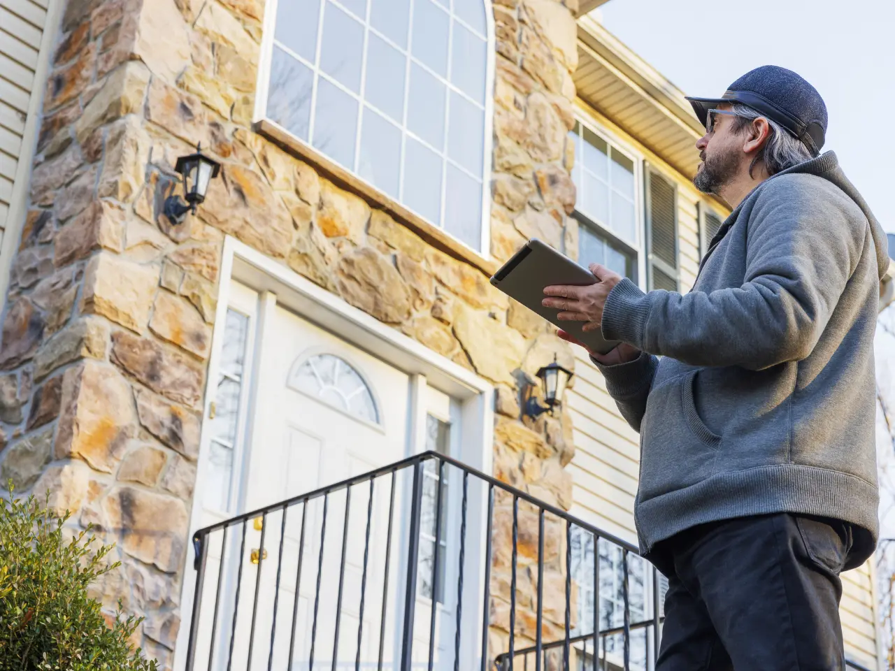 Inspector with a tablet looking over the exterior of a house
