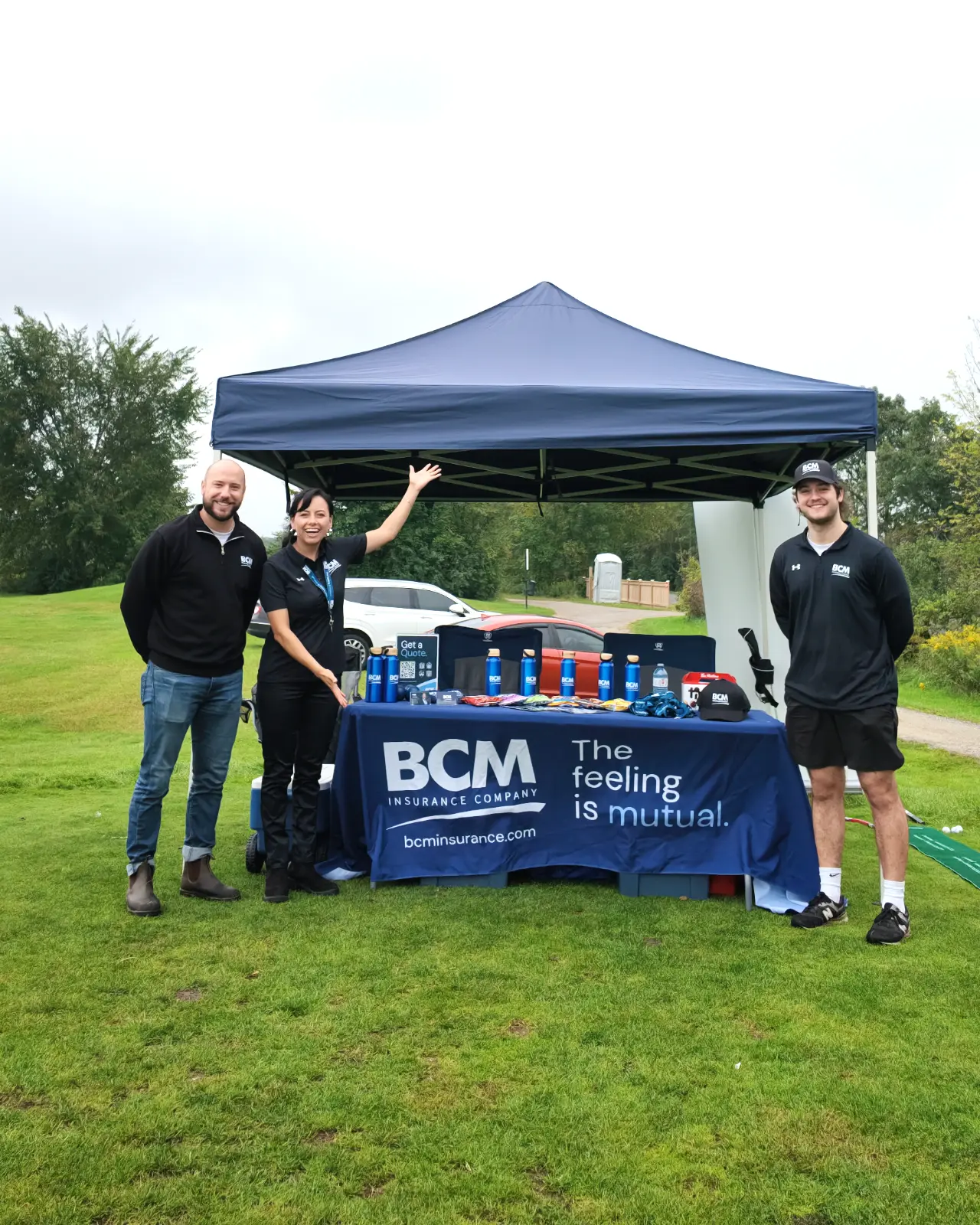 Three BCM Insurance staff at the BCM tent on a golf course